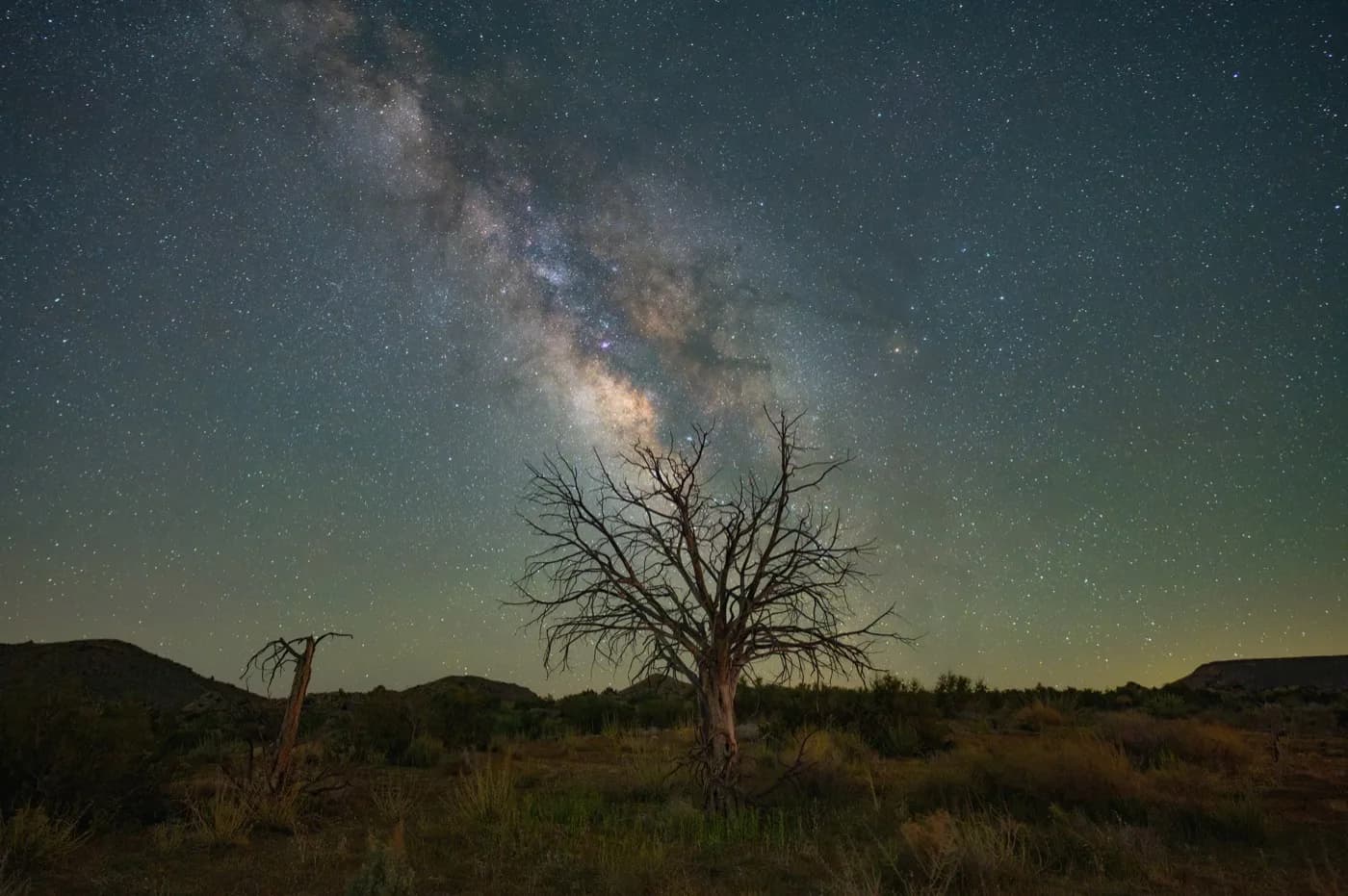 The Milky Way stretching above a dark desert landscape